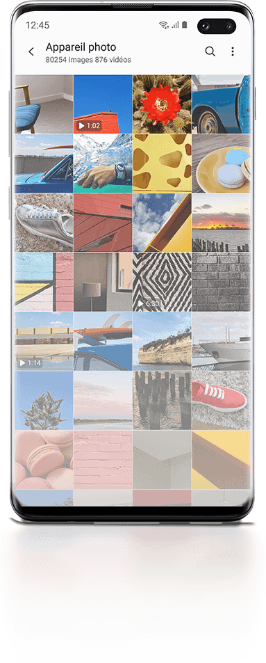 Galaxy S10 plus vu de face avec l'interface Galerie illustrée à l'écran avec 28 photos. Derrière le téléphone, plus de photos sont montrées et s'estompent en arrière-plan pour indiquer que vous pouvez stocker beaucoup de photos.