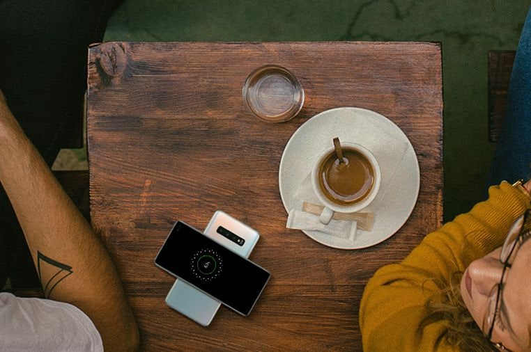 Image d'un homme et d'une femme dans un café avec un café sur la table et deux téléphones Galaxy S10 plus, l'un partageant un pouvoir avec l'autre.
