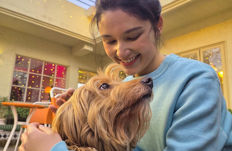 Portrait d’une femme et d’un chien à l’extérieur. Le teint de la peau et les textures sont bien capturés.