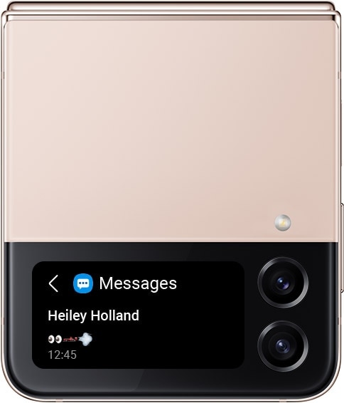 Un Galaxy Z Flip4 en Or Rose plié avec une notification de SMS sur l’écran extérieur. Il présente une série de caractères emoji : yeux, voiture de course et vent.