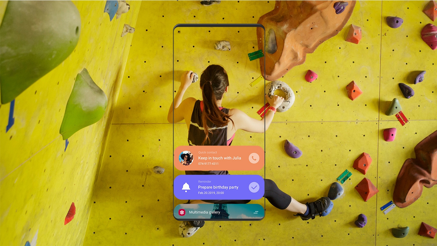 실내 암벽 등반을 하는 여성의 이미지와 빅스비 홈에서 빠른 연락처, 리마인더, 멀티미디어 갤러리 앱이 실행되는 모습이 담긴 스마트폰의 전면 화면