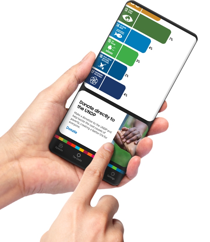 Un par de manos sostiene un teléfono inteligente Galaxy que muestra la aplicación Samsung Global Goals. El dedo índice de una mano está tocando una tarjeta promoviendo donaciones directas a los objetivos. Además de aumentar los ingresos publicitarios como una donación, los usuarios pueden enviar sus propias donaciones directamente a los objetivos.