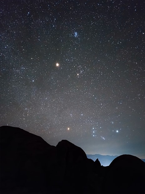 Una foto de un paisaje nocturno con la silueta de un terreno montañoso en primer plano. Detalles del cielo estrellado se capturan claramente en alta resolución gracias a Expert Raw. La foto se tomó con el Galaxy S23 plus utilizando el modo panorámico con un diafragma de F 1.8.