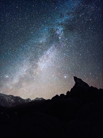 A night landscape photo with the silhouette of mountainous terrain in the foreground. Details of the starry sky are clearly captured in high-resolution detail with Expert Raw. The photo was taken with Galaxy S23 Ultra using wide mode with an aperture of F 1.7.