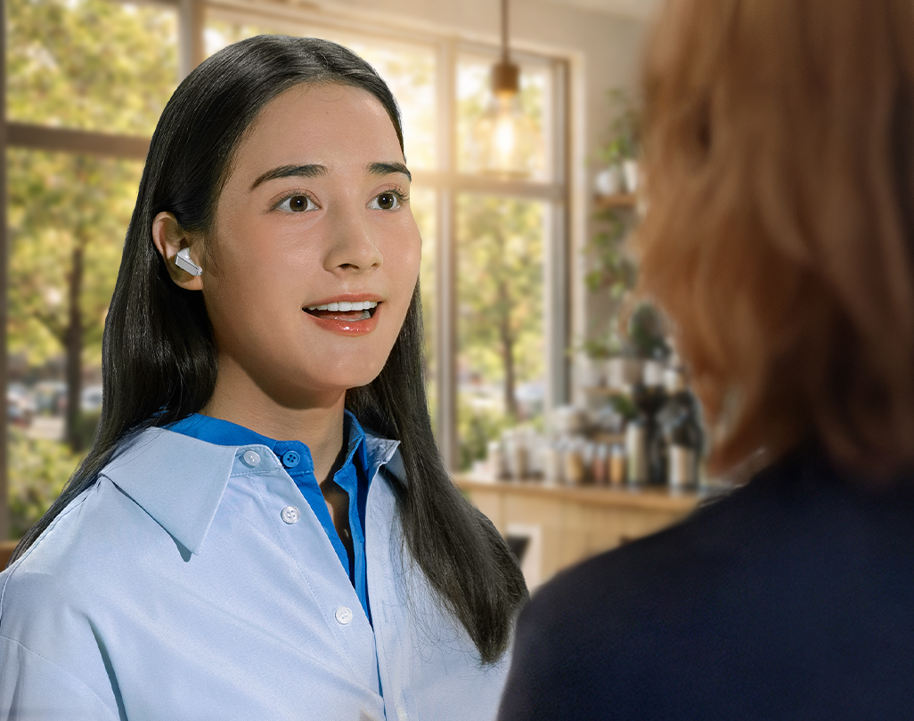 Une femme utilisant un Galaxy Buds4 Pro blanc tout en tenant une conversation avec une autre personne, mettant en valeur la fonctionnalité Voice Detect.