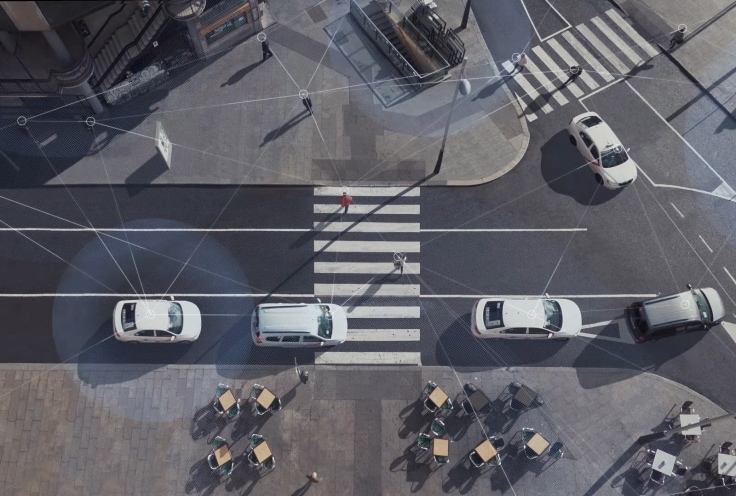 Photo aérienne d’une scène urbaine avec des voitures qui circulent et des piétons qui marchent, avec la superposition de lignes en hauteur pour illustrer la connectivité des réseaux WiFi et LTE.