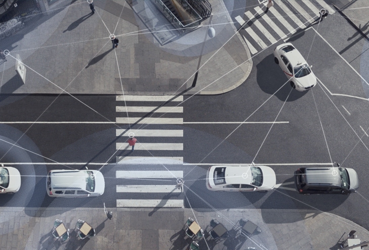 Foto aérea de uma cena de rua com carros passando e pessoas andando, com linhas sobrepostas no topo para mostrar a conectividade de Wi-Fi e LTE. 