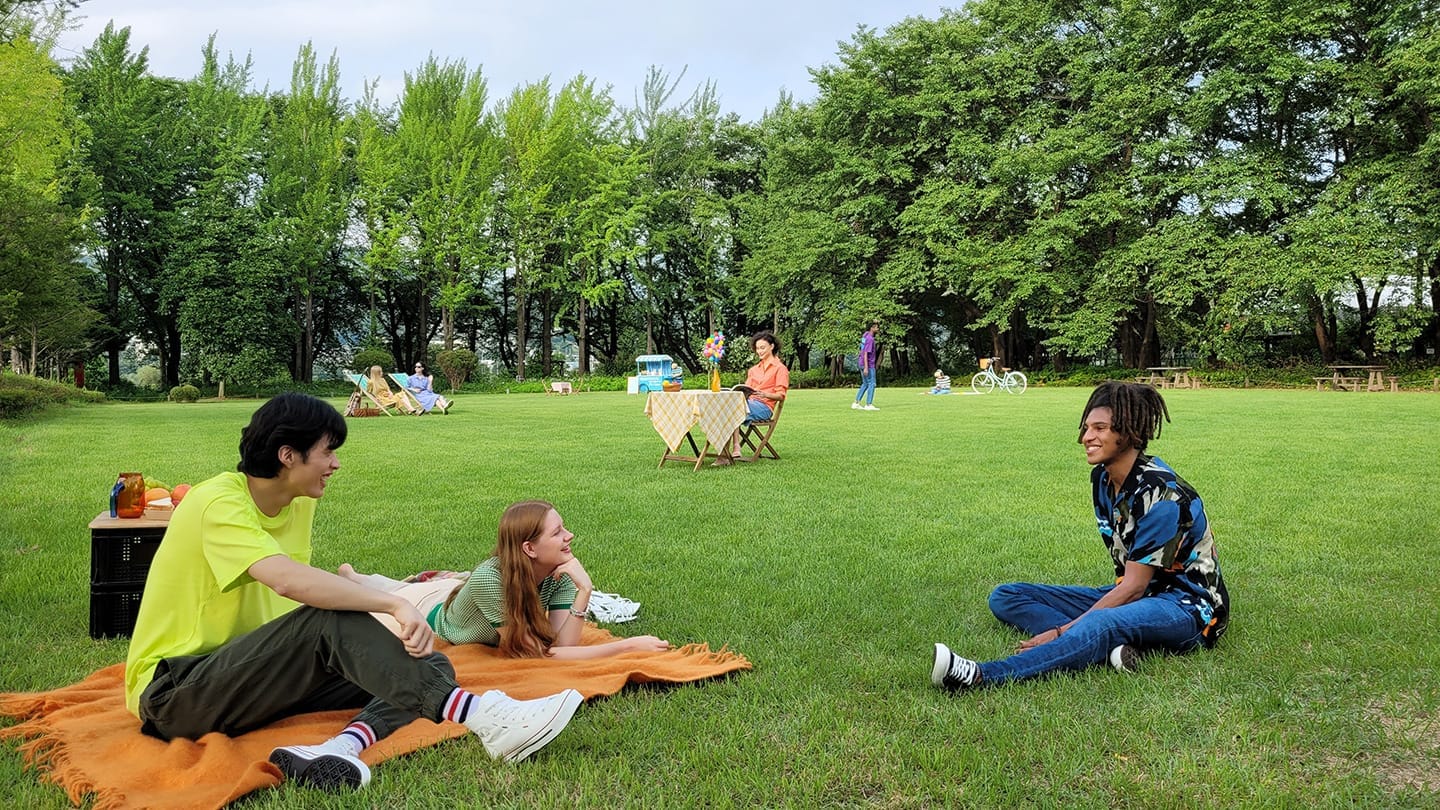 Foto de pessoas sentadas em um parque, sem zoom.