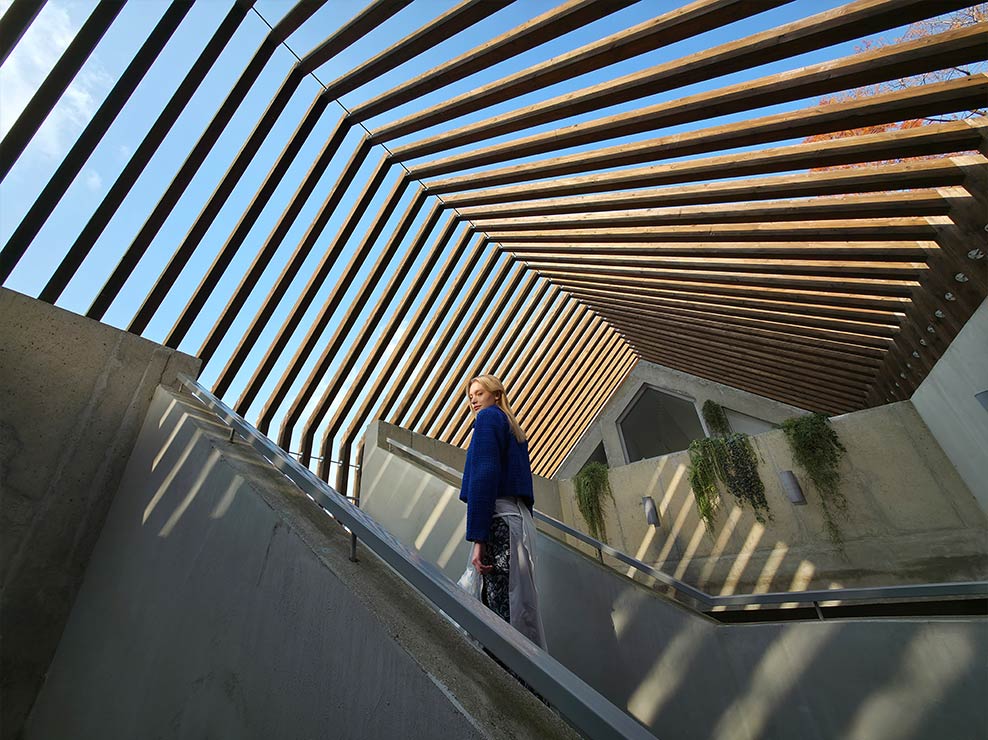 Photo ultra grand-angle d’une femme contre un bâtiment structuré. Les détails sont clairs grâce à la haute résolution.