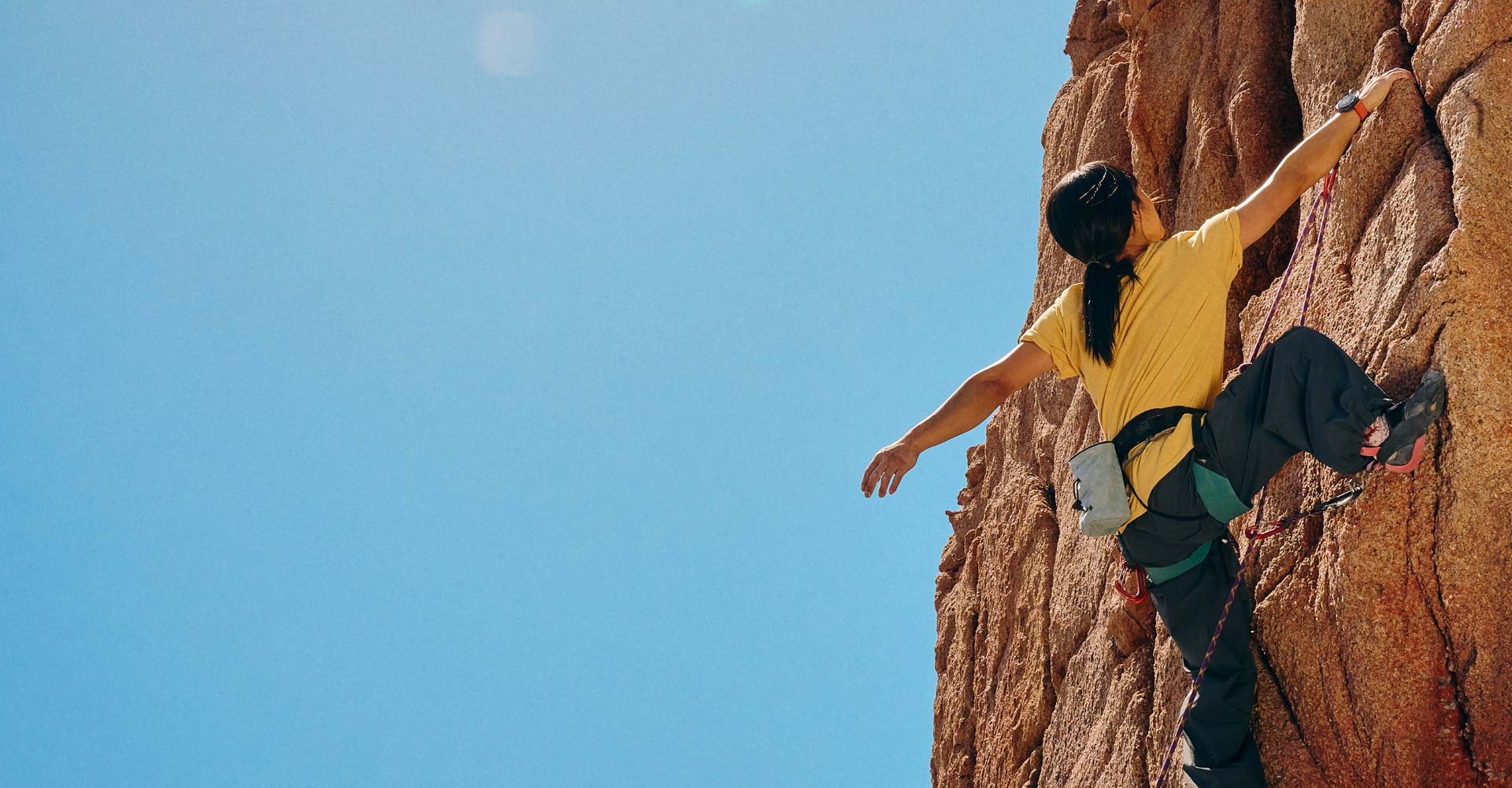 Una mujer escala rocas con un Galaxy Watch Ultra en la muñeca.