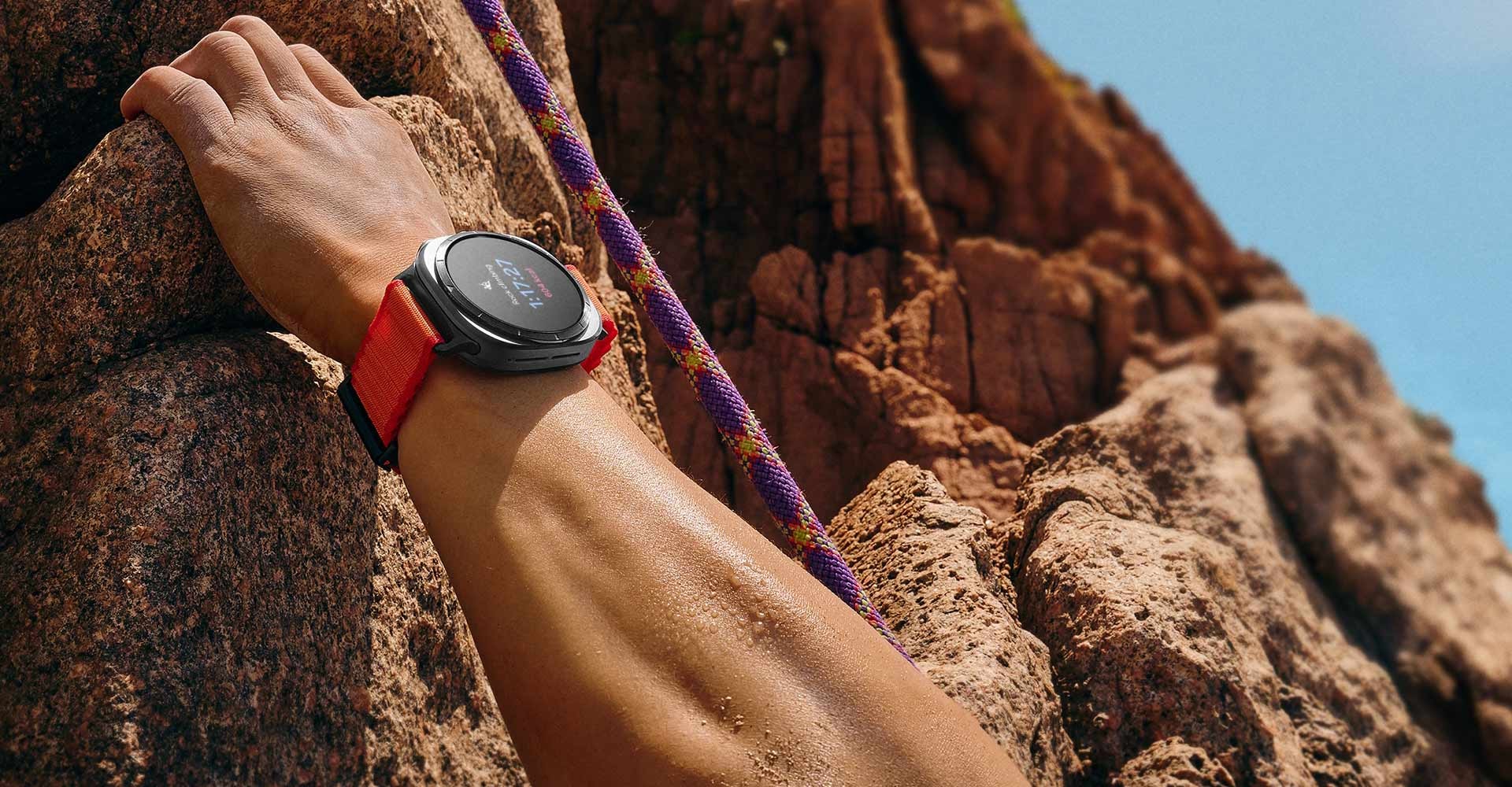 Una mano que se sujeta de una roca en la montaña lleva un Galaxy Watch Ultra en la muñeca.