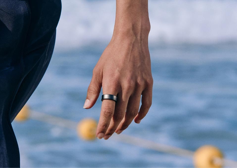 Uživatel se prochází po pláži s prstenem Galaxy Ring nasazeným na prstu.