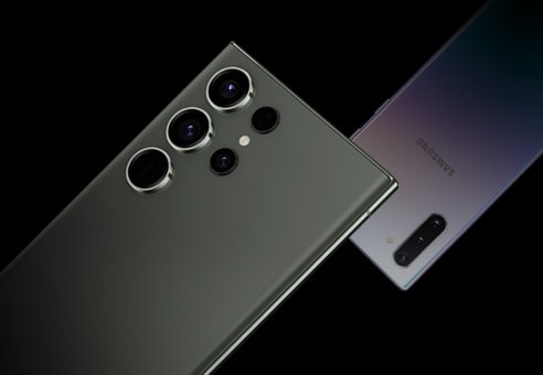 Ein älteres Galaxy Smartphone von vorne gesehen und das Galaxy S23 Ultra von hinten gesehen. Die Smartphones sind in entgegengesetzte Richtungen zueinander gerichtet.