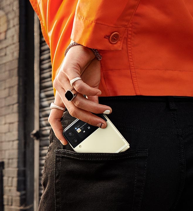 Die Hand eines Mannes schiebt ein Galaxy Z Flip3 5G in die Gesäßtasche seiner Jeans.