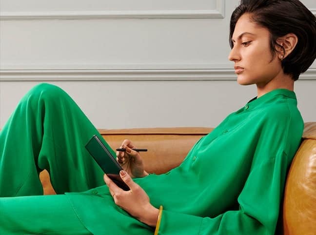 Eine Frau sitzt auf einer Couch und skizziert etwas mit dem S Pen Fold Edition auf dem aufgefalteten Galaxy Z Fold3 5G.