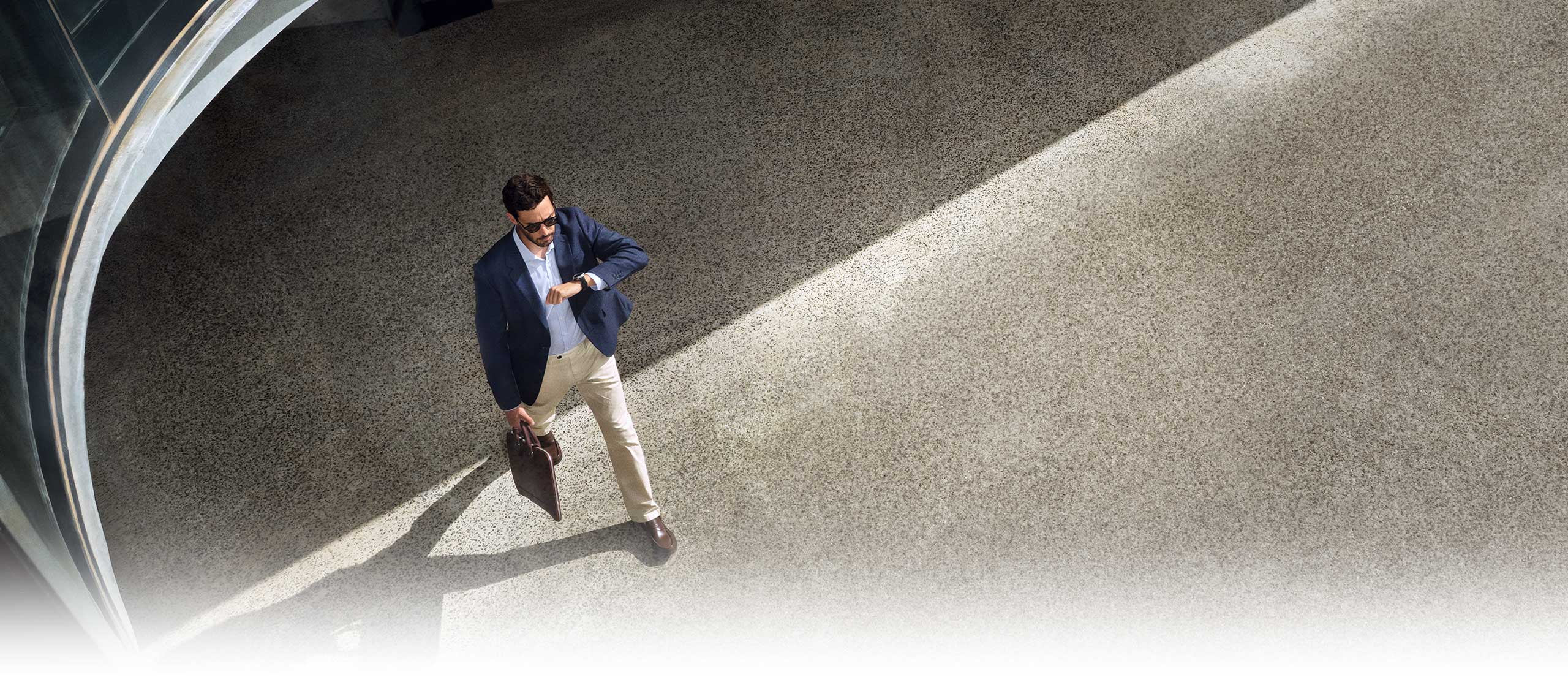 Una persona con atuendo informal de negocios mira su reloj inteligente Galaxy Watch8 Classic mientras camina.