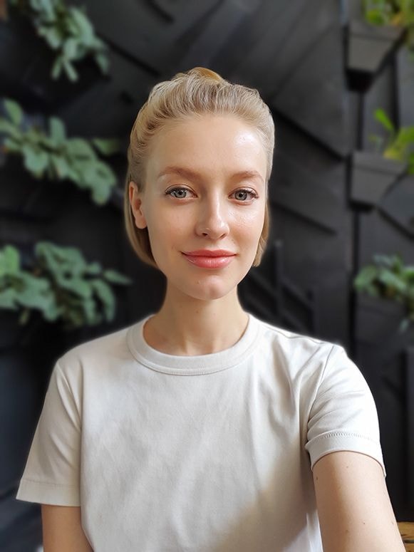 Selfie avec la mise au point en direct rÃ©alisÃ©e avec le Galaxy S10 plus dâune femme debout devant un mur entourÃ© de plantes. Le mur est floutÃ© mais la femme est clairement visible.