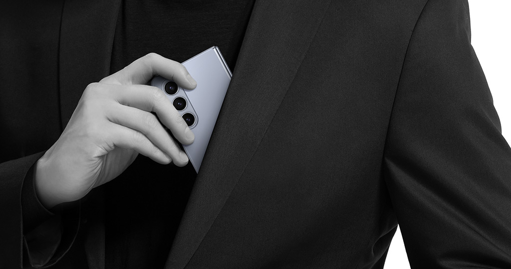 A folded Galaxy Z Fold5 is removed from the inner chest pocket of a blazer.