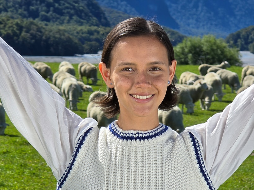 A close-up portrait a woman with an open field and mountains in the background taken at 10x optical quality zoom.
