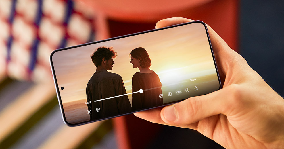 O Galaxy S24 plus é mantido ao ar livre, sob a luz do sol. Um vídeo com cores ricas e alto contraste é reproduzido na tela.
