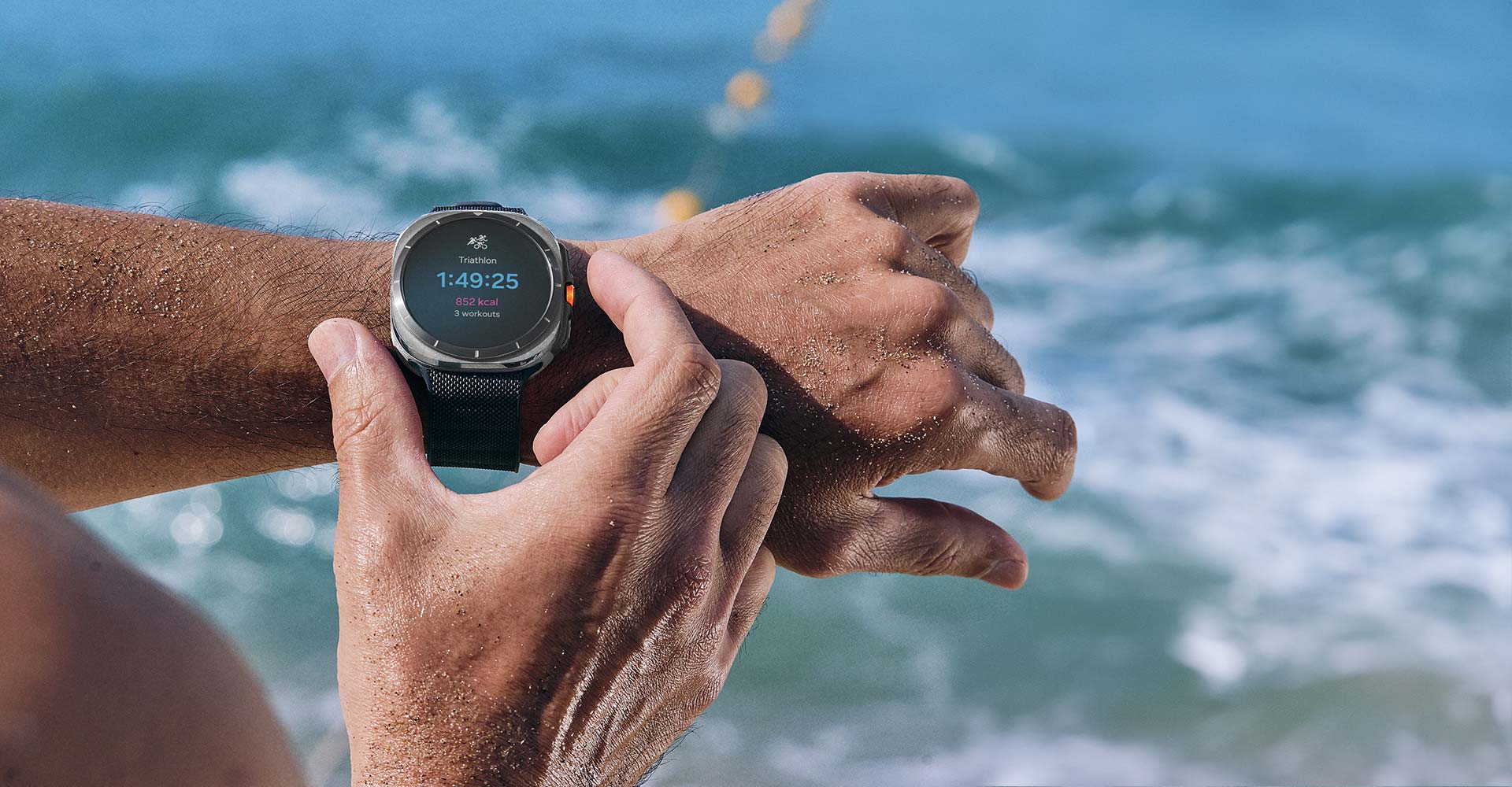 יד מבצעת תנועה ללחיצה על הלחצן המהיר בשעון Galaxy Watch Ultra שנמצא על פרק כף היד. מסך מעקב אימון הטריאתלון מוצג בשעון.