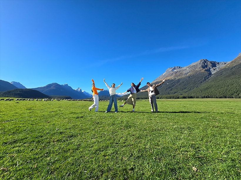 A photo of an open field and mountains with figures near the horizon taken at 0.6x zoom.