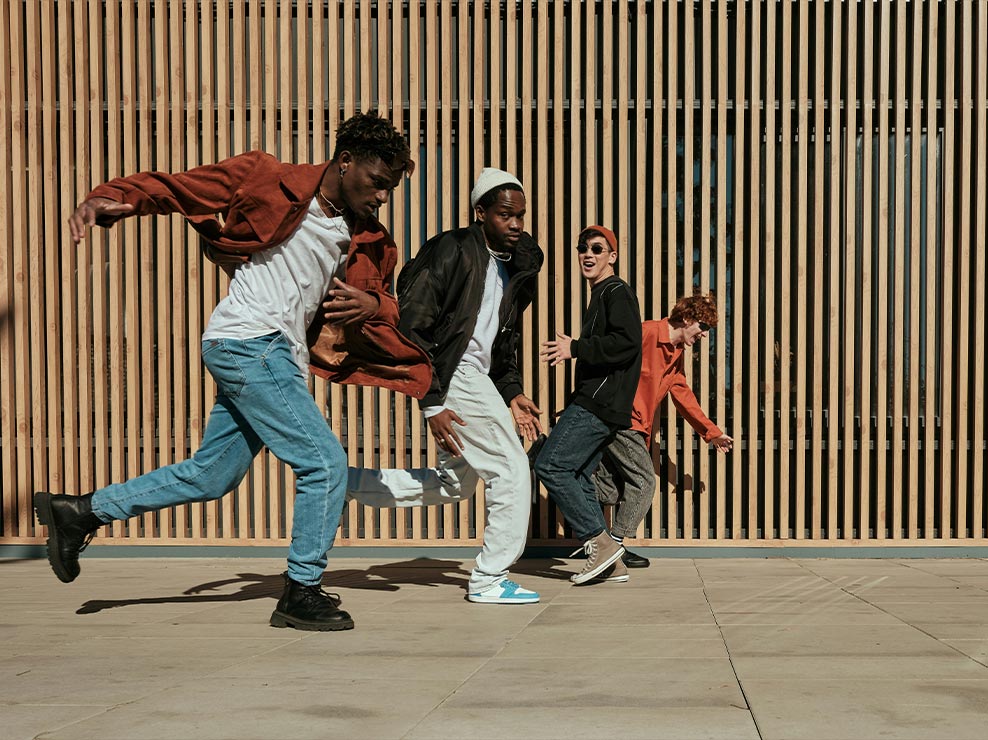 Фотография четырех мужчин, бегущих вдоль стены из деревянных панелей, четкая, яркая и полная деталей.