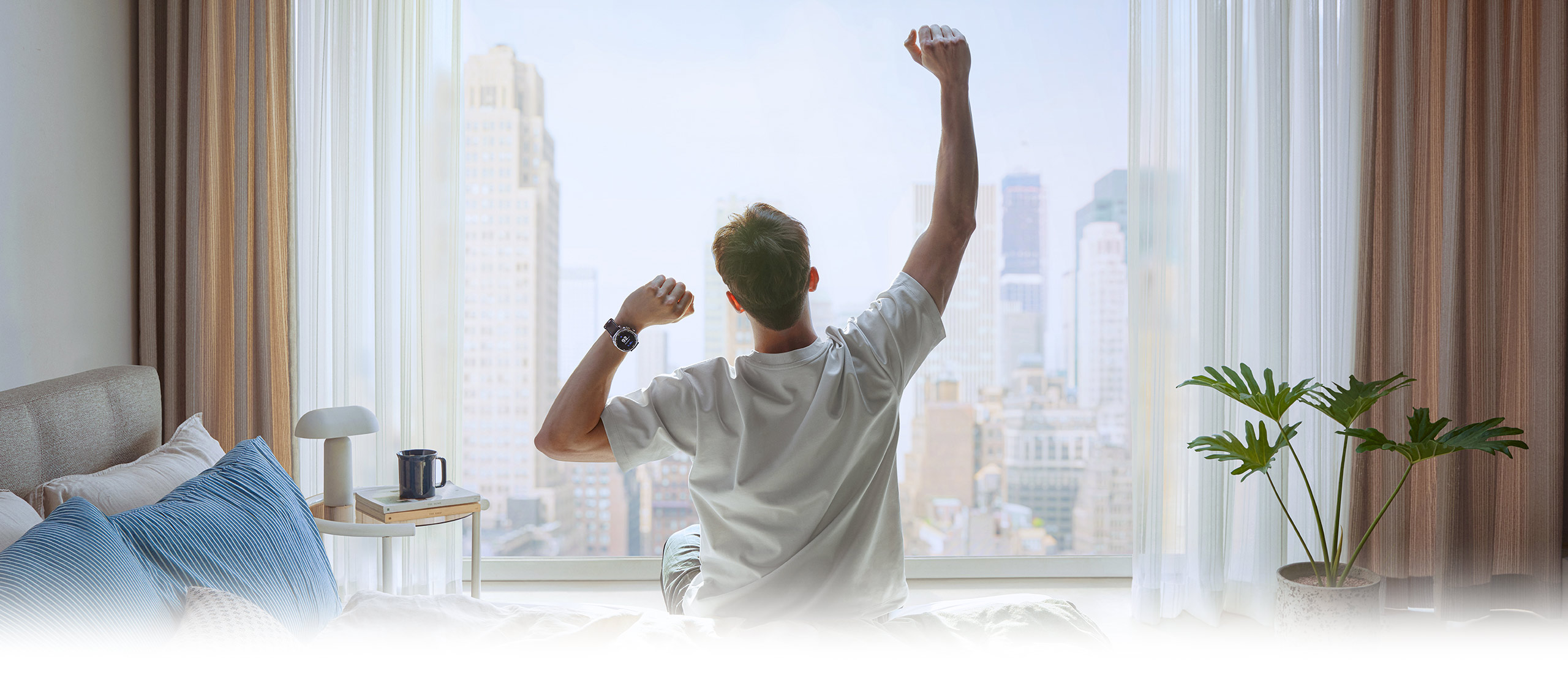 A person stretching his arms out in the morning, facing the window. On one wrist is Galaxy Watch8 Classic.