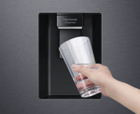 Una persona toca el botón del dispensador con la taza para obtener agua fría y refrescante del dispensador de agua.