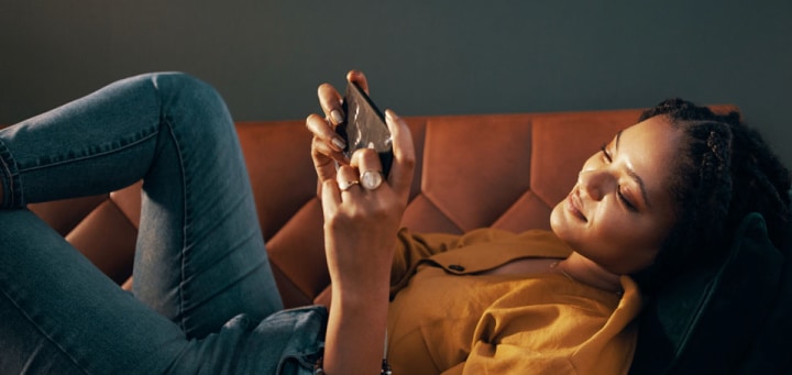 mujer acostada en un sillón, mirando su smartphone galaxy