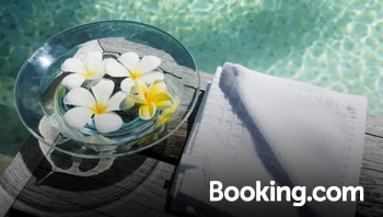 A bowl of flowers and a towel is seen near a swimming pool