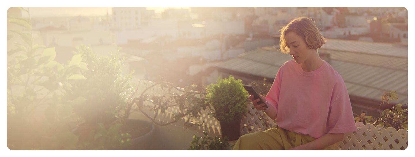 فتاة مع هاتف سامسونج على سطح بناية بالعرض