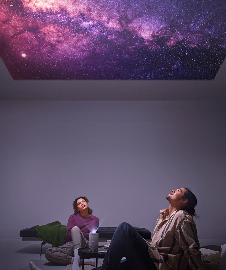 "رجل وامرأة يتأملان النجوم وهي تتألق في السقف عبر جهاز The Freestyle. "