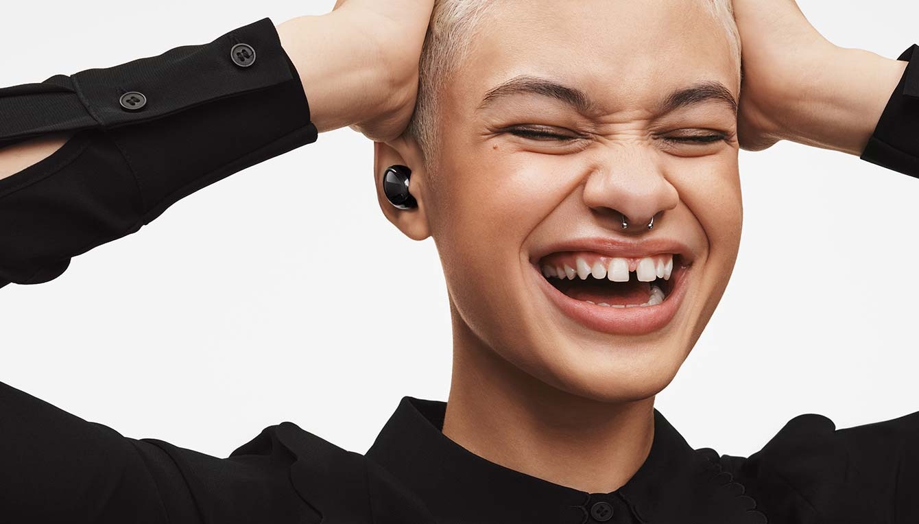 Woman wearing Galaxy Buds Pro in Phantom Black, smiling widely.