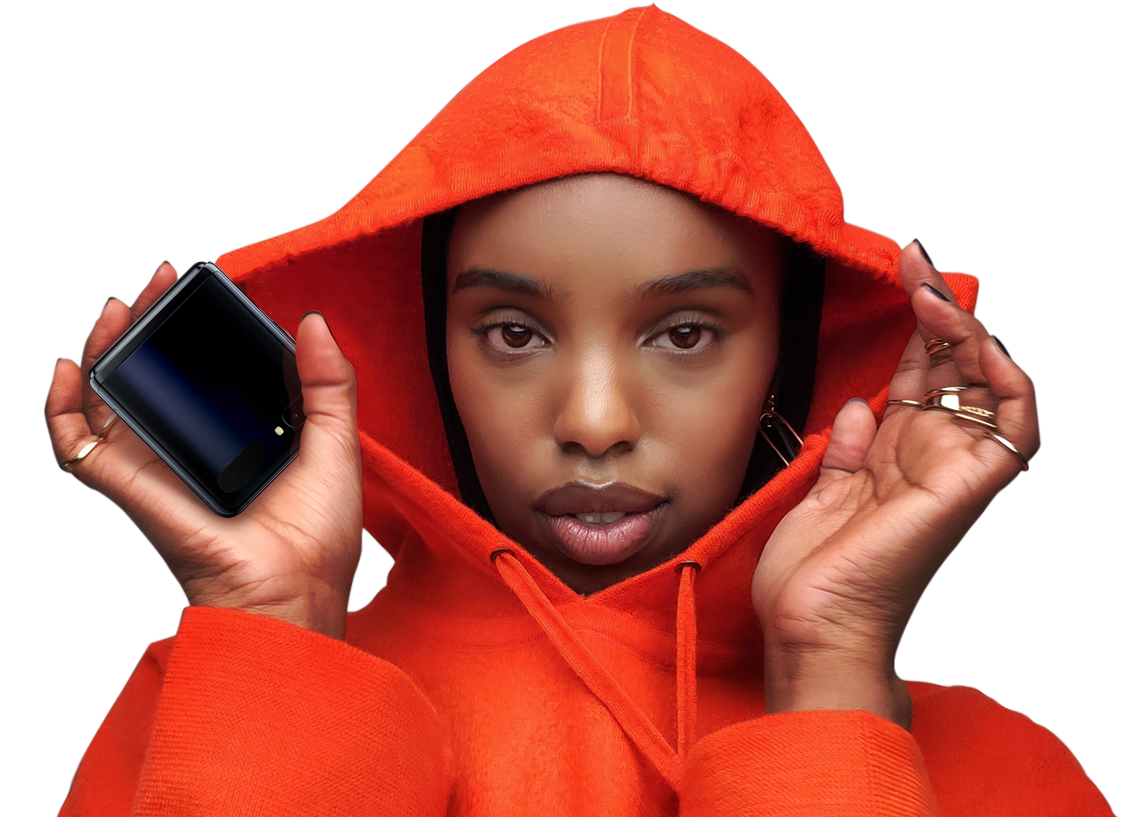 A woman in an orange hoodie with Galaxy Z Flip in her hand.