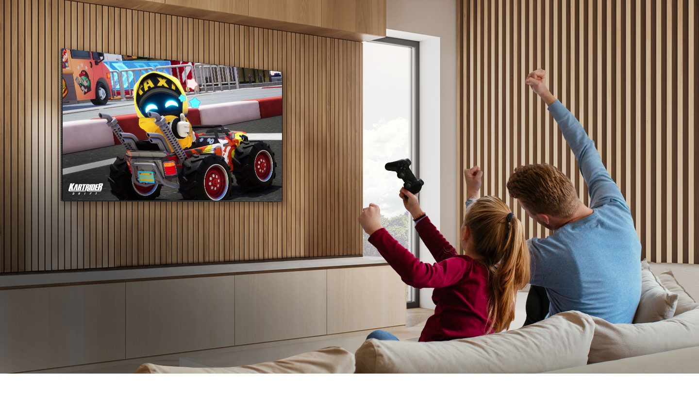Ein Kind und ein Elternteil sind mit Freude an einem Spiel im Fernsehen dabei, bei dem drei KartRider-Figuren auf dem Bildschirm zu sehen sind.