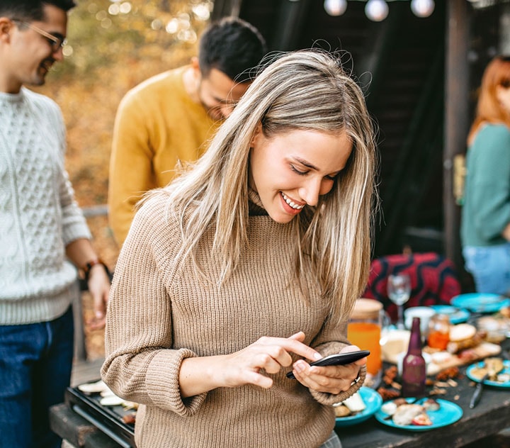 A woman texting during a party with Bixby’s assistance.