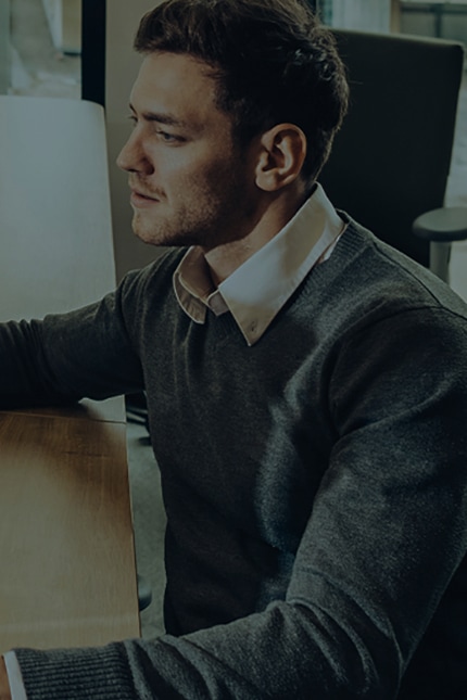 A man dressed neatly is sitting down in the office, focused on work.