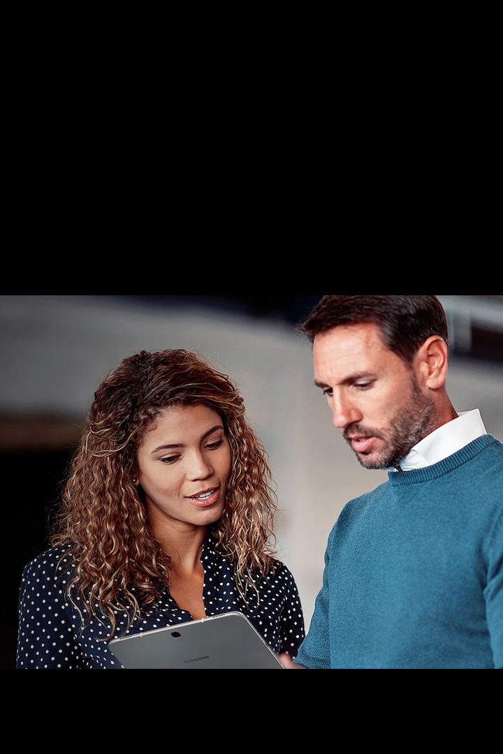 Two young professionals working together. One has a Galaxy Tablet and another person looking at the tablet.