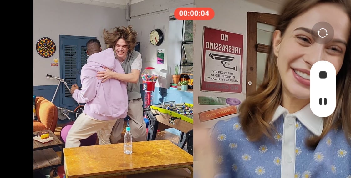 Scene of a house with three friends recorded by Galaxy S21 FE 5G with Dual Recording. The camera view is split in two, showing a man flipping a water bottle on a table, and another man and a woman reacting to it when he lands it