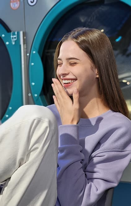 A woman laughing in a laundromat, taken in Portrait Mode with Blur effect applied.