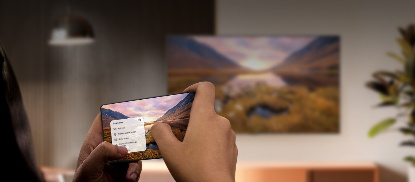 Een Galaxy-smartphone die een prachtig landschapsbeeld op een Samsung tv op de achtergrond werpt. De tv toont dezelfde afbeelding in liggende positie. 