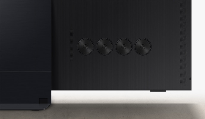 We zien een close-up van vier ronde speakers die zijn ingebouwd in een TV.