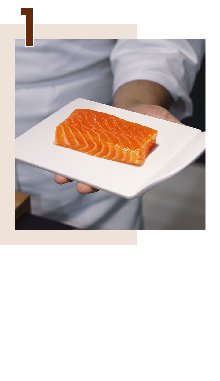'Étape 1. Une main tenant une assiette avec un filet de saumon frais.