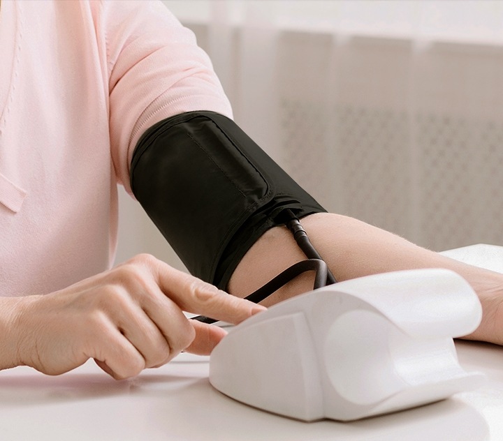 Uma mulher verificando sua pressão arterial com um monitor digital portátil de pressão arterial. 
