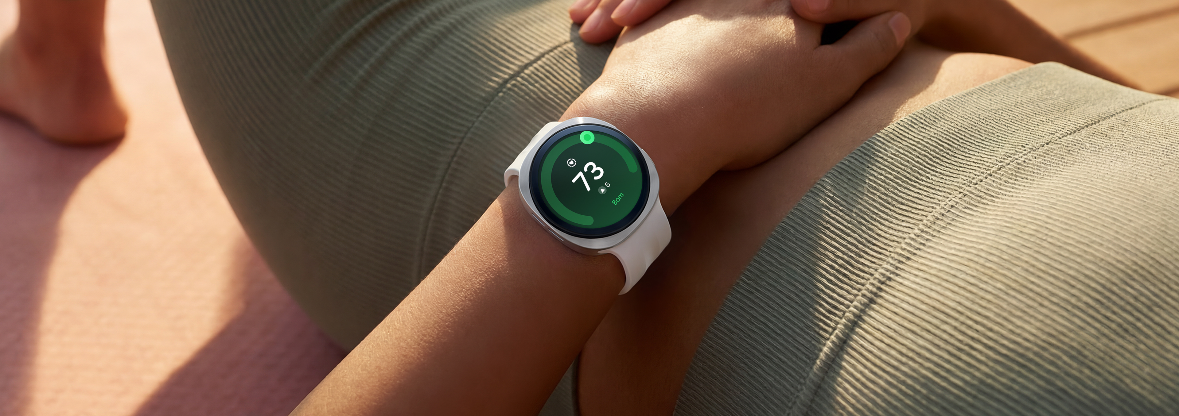 Uma pessoa deitada de costas está usando o Galaxy Watch9 em Prata com uma Pulseira Sport em Cream no pulso, e uma Pontuação da saúde do coração de 73 é exibida na tela do relógio, mostrando os recursos de monitoramento de saúde do coração do Galaxy Watch9.