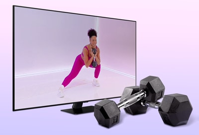 Person working out on a Samsung TV with weights next to it