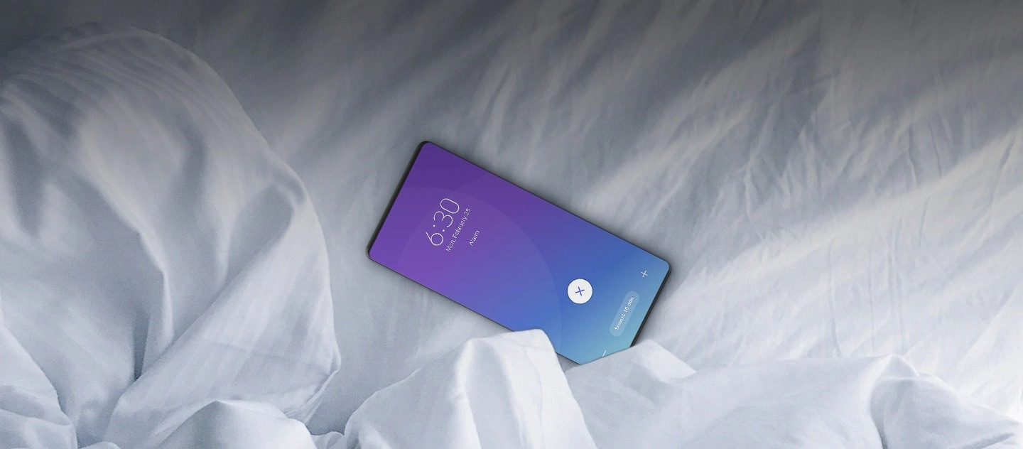 A Galaxy smartphone on white bedsheets with the 6:30 A.M alarm ringing.