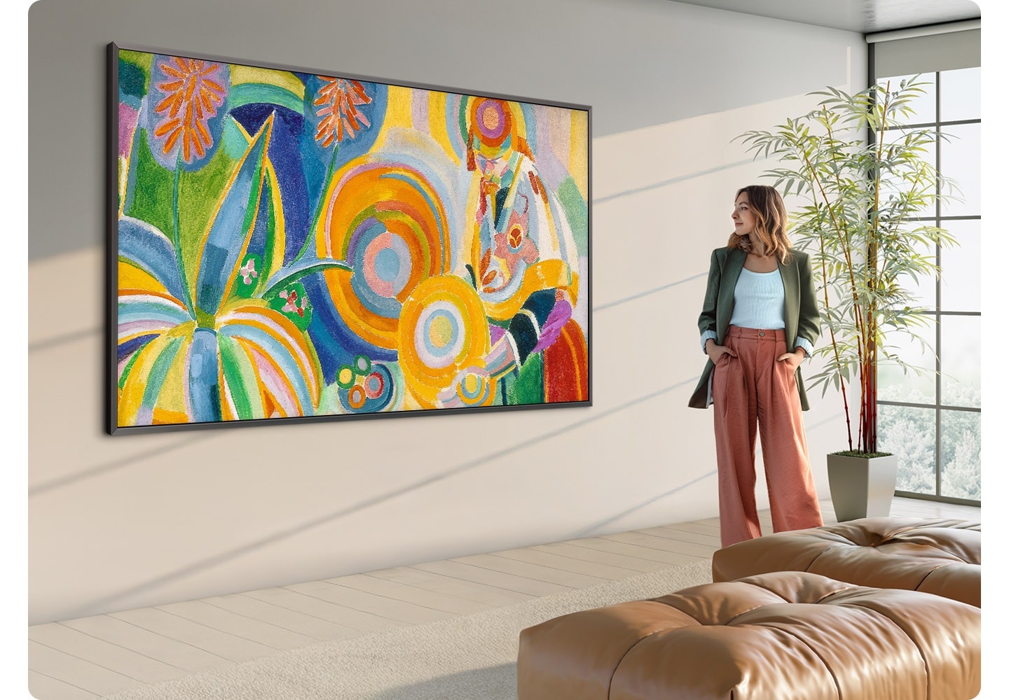 A large 98-inch The Frame TV displaying artwork in a bright modern living room, with a person standing nearby viewing the piece.