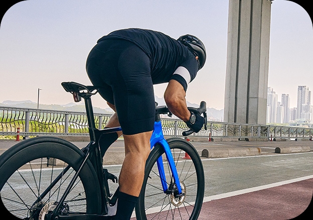 Un homme en tenue de cycliste roule sur un vélo de course sur une piste cyclable.